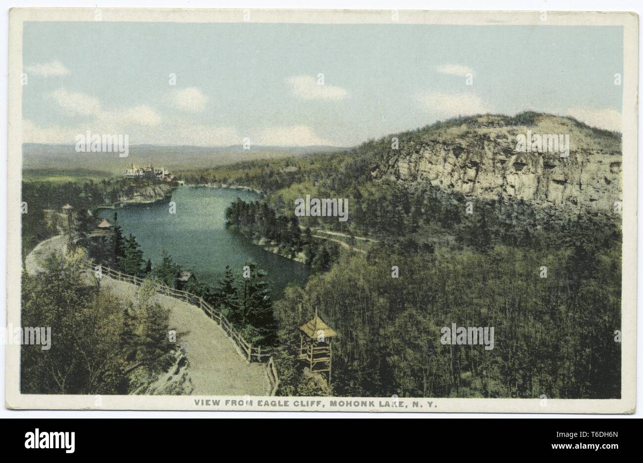 Postkarte mit einem Bild von einem Blick vom hohen Aussichtspunkt der "Eagle Cliff, "Blick nach unten in Richtung der Mohonk Lake Trail, mit Mohonk See und Mohonk Mountain House im Hintergrund sichtbar, und Nadelbäumen oder Pinien und einem kalkhaltigen weißen Felsen im Vordergrund; auf Mohonk Lake, New York, 1914. Von der New York Public Library. () Stockfoto