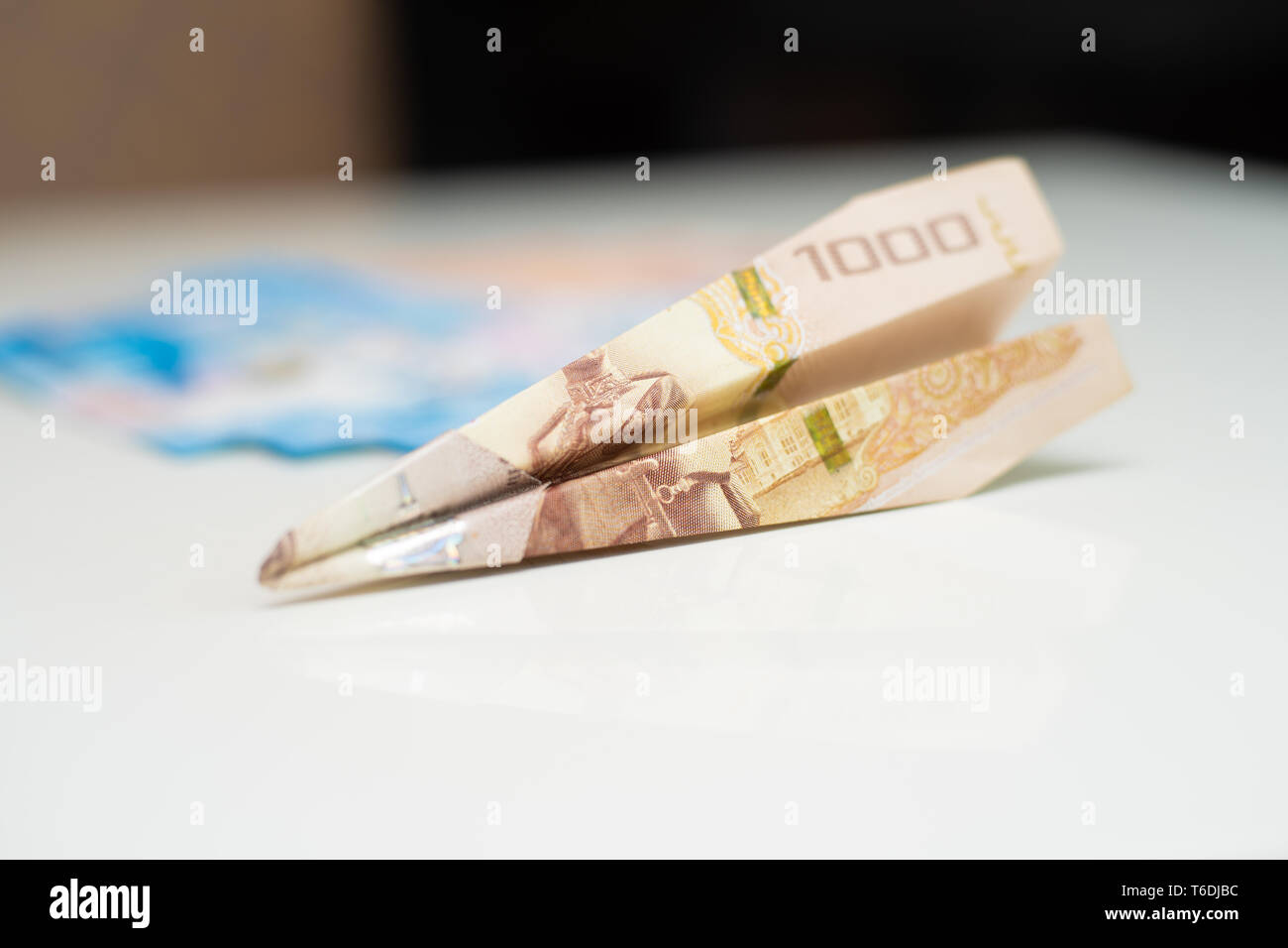 Thai 1000 Baht in Form eines Flugzeugs, gefaltet, der lag auf einem weißen Tisch Stockfoto