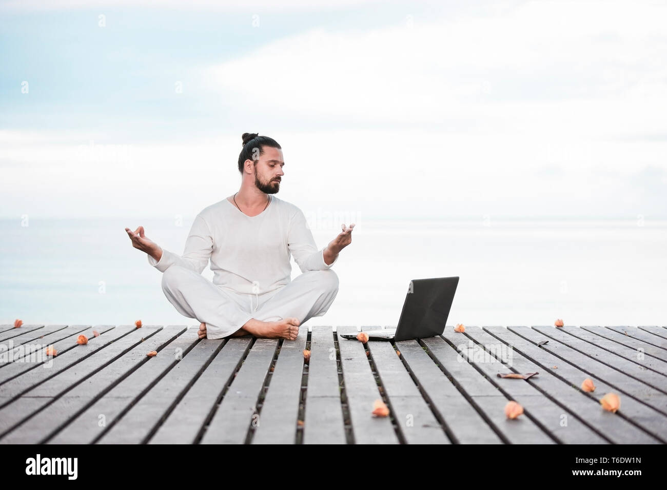 Mann in weißer Kleidung Meditation Yoga auf hölzernen Pier Stockfoto
