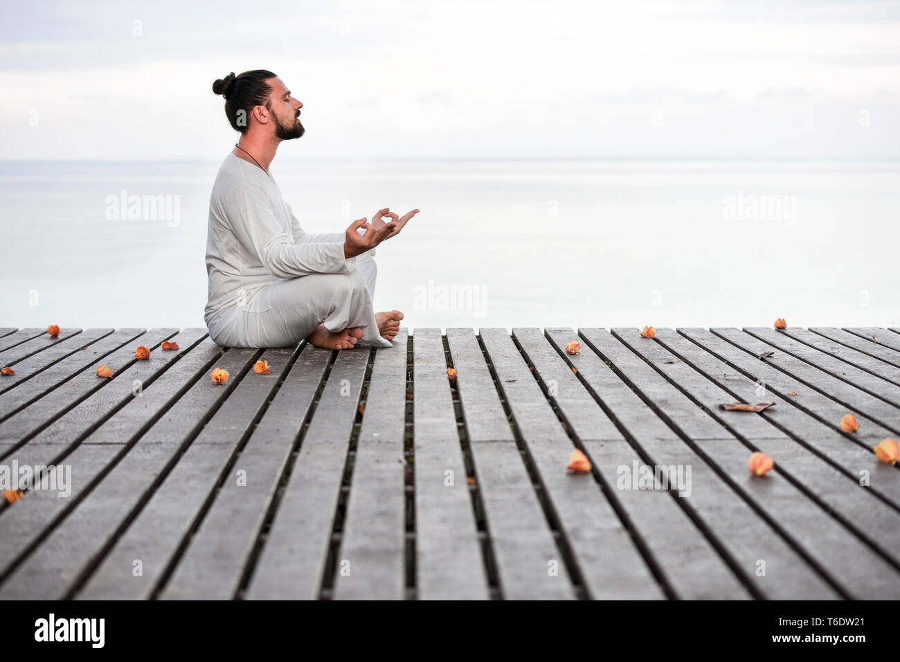 Mann in weißer Kleidung Meditation Yoga auf hölzernen Pier Stockfoto