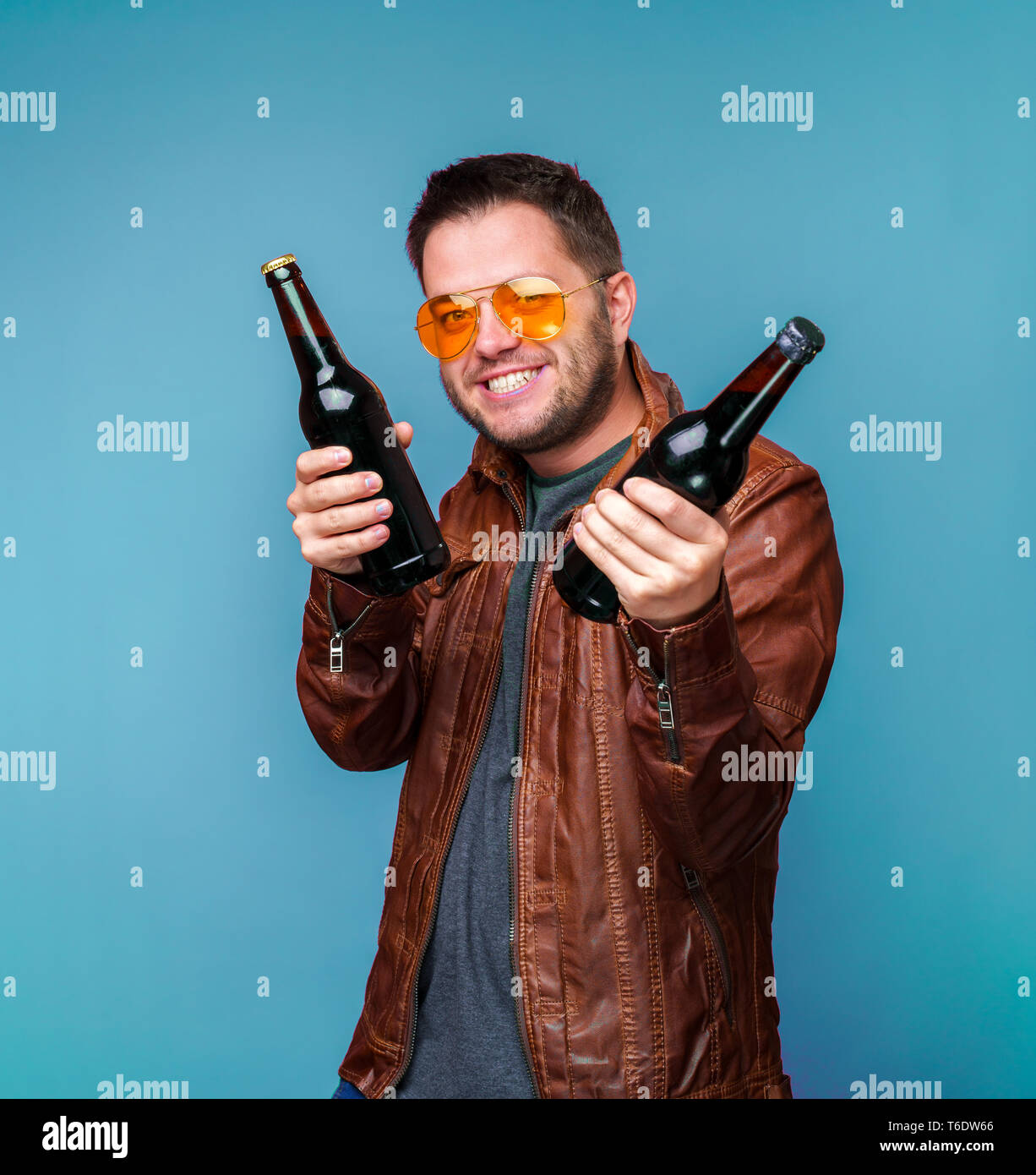 Fotos von lächelnden Mann in orange Gläser und Lederjacke mit zwei Flaschen in der Hand Stockfoto