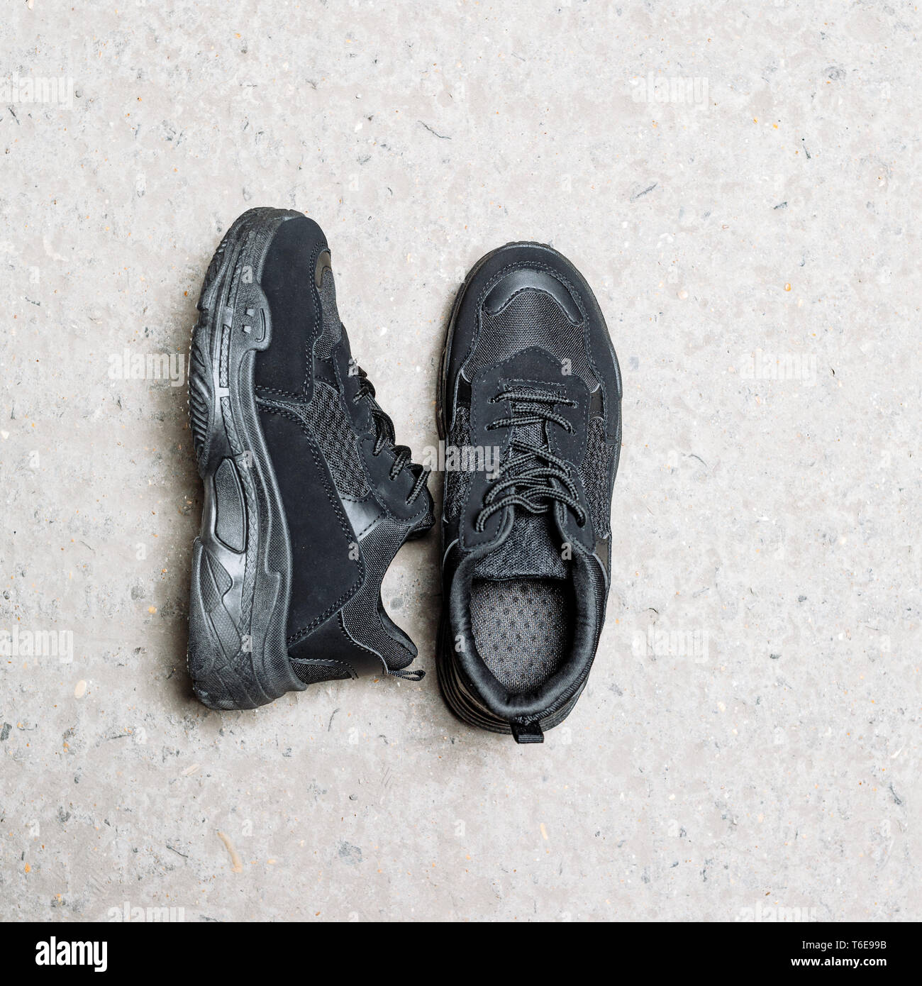 Schwarze Sneakers auf eine dicke schwarze Sohle auf einer konkreten Hintergrund Stockfoto