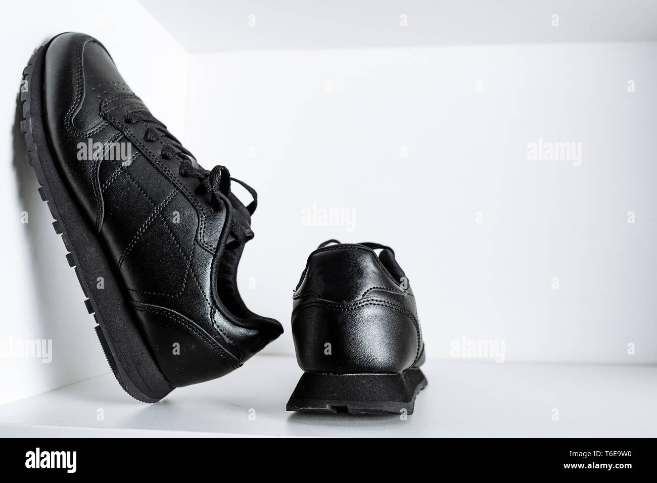 Ein Paar schwarze fashion Sneaker mit schwarzer Spitze auf ein weißes Regal im Store Stockfoto
