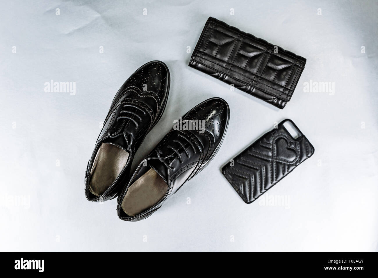 Ein paar elegante schwarze Schuhe perforiert, Schnürer, den Geldbeutel und ein Phone Case auf weißem Hintergrund Stockfoto