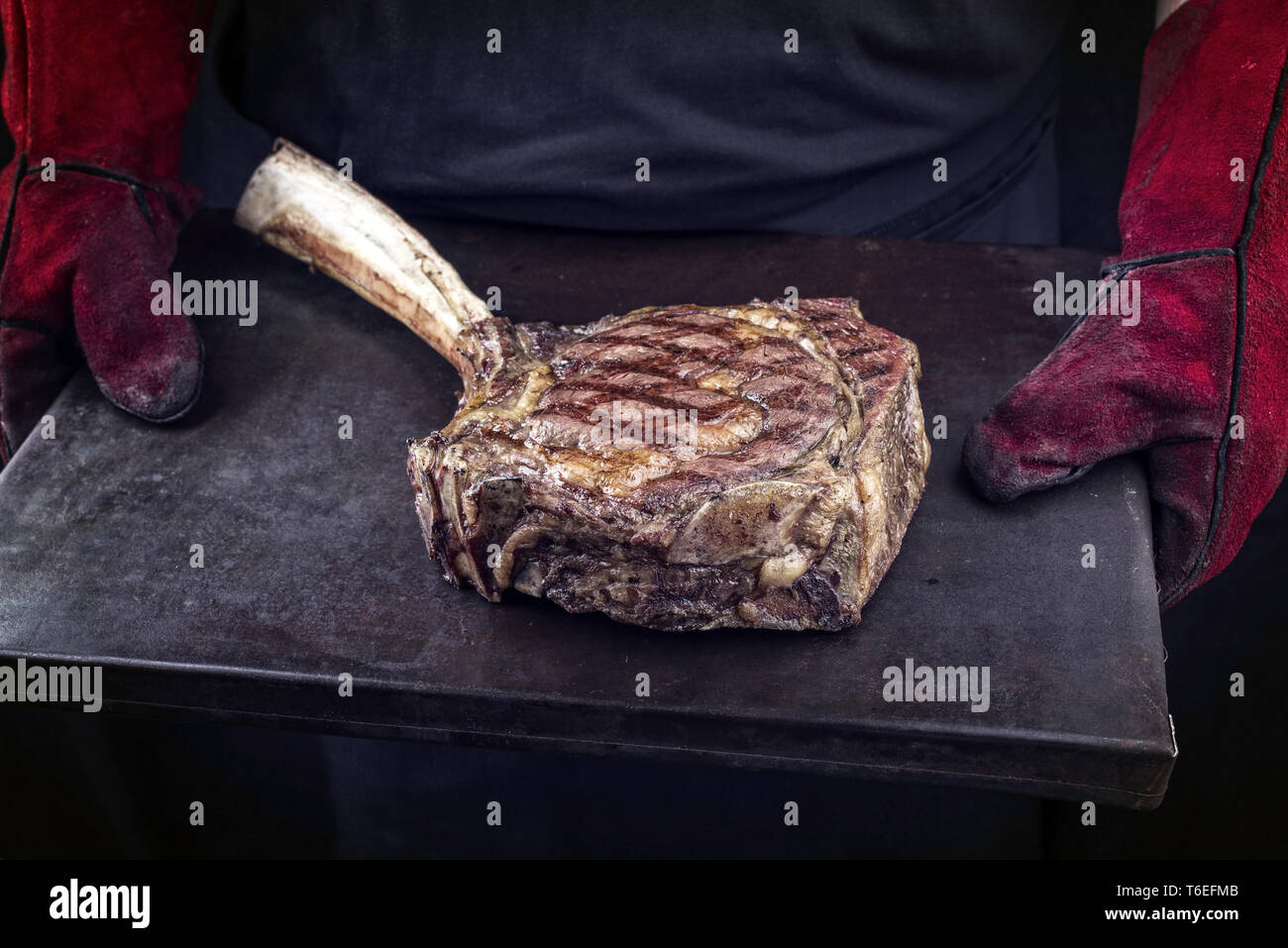 Mann hält Grill Wagyu Tomahawk Steak auf dem alten Blech in seine Hände mit Handschuhen Stockfoto