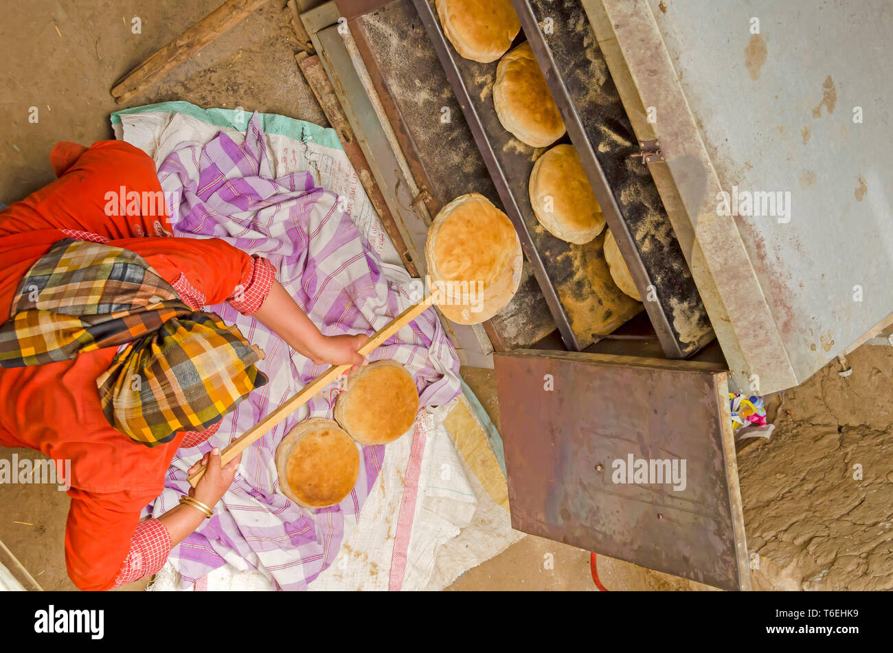Ägyptische Frau backt runde Brote von Aish Baladi Brot in kleinen Ofen zu Hause Stockfoto