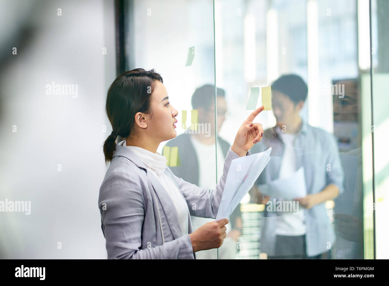 Jungen asiatischen Business woman Planung mit Haftnotizen mit Kollegen sprechen außerhalb der Tagungsraum. Stockfoto