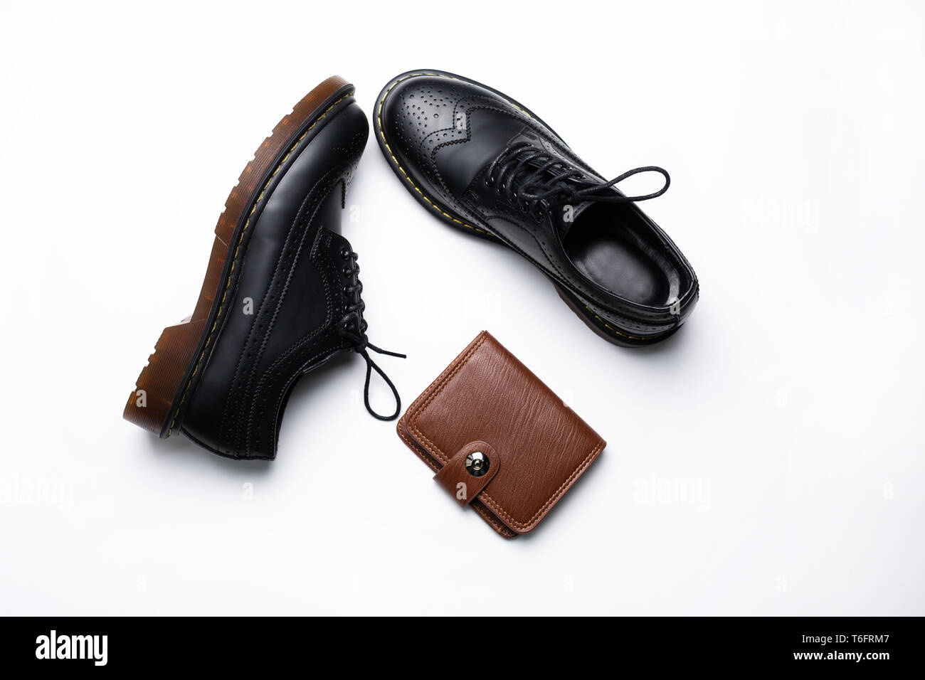 Modische Leder schwarz Derbys mit PU-Sohlen und eine braune Geldbörse mit einer Taste auf einem weißen Hintergrund Stockfoto