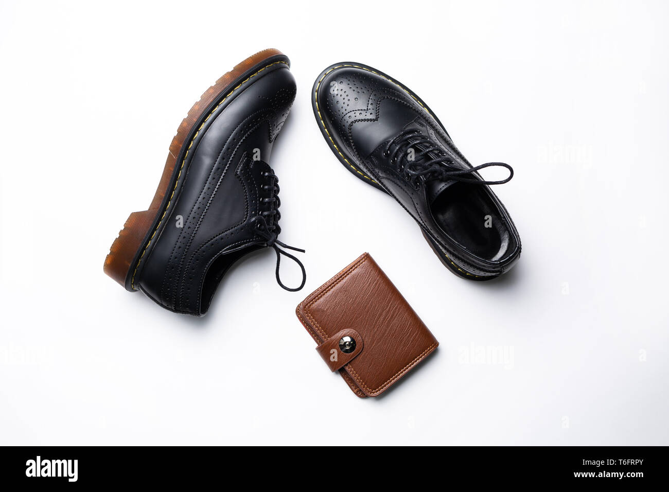 Modische Leder schwarz Derbys mit PU-Sohlen und eine braune Geldbörse mit einer Taste auf einem weißen Hintergrund Stockfoto