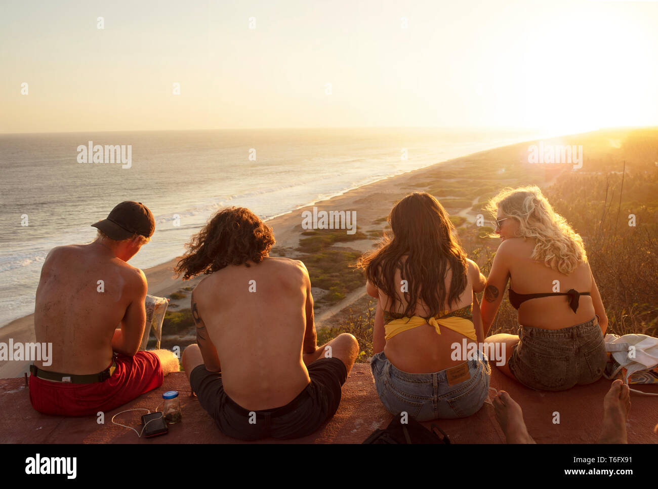 Ansicht der Rückseite des junge Reisende, Spaß und Lachen, genießen die Aussicht auf die Küste bei Sonnenuntergang. Outdoor Lifestyle Konzept. Chacahua, Mexiko. Apr 2019 Stockfoto
