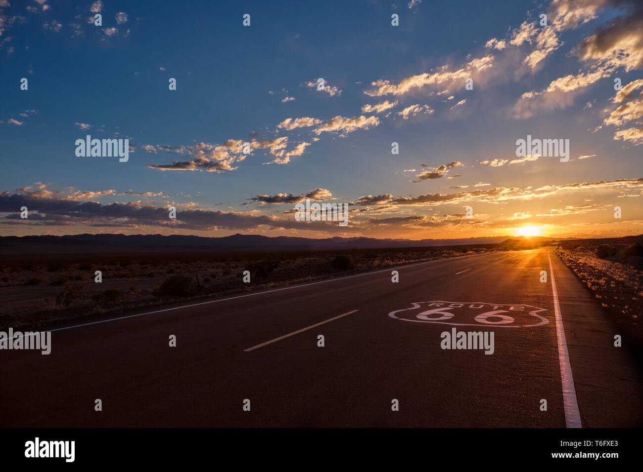 66 Pflaster Zeichen im Vordergrund Route und den abnehmenden Perspektive der Straße, die zu einem dramatischen Sonnenuntergang in der Mojave Wüste außerhalb der Ambo Stockfoto