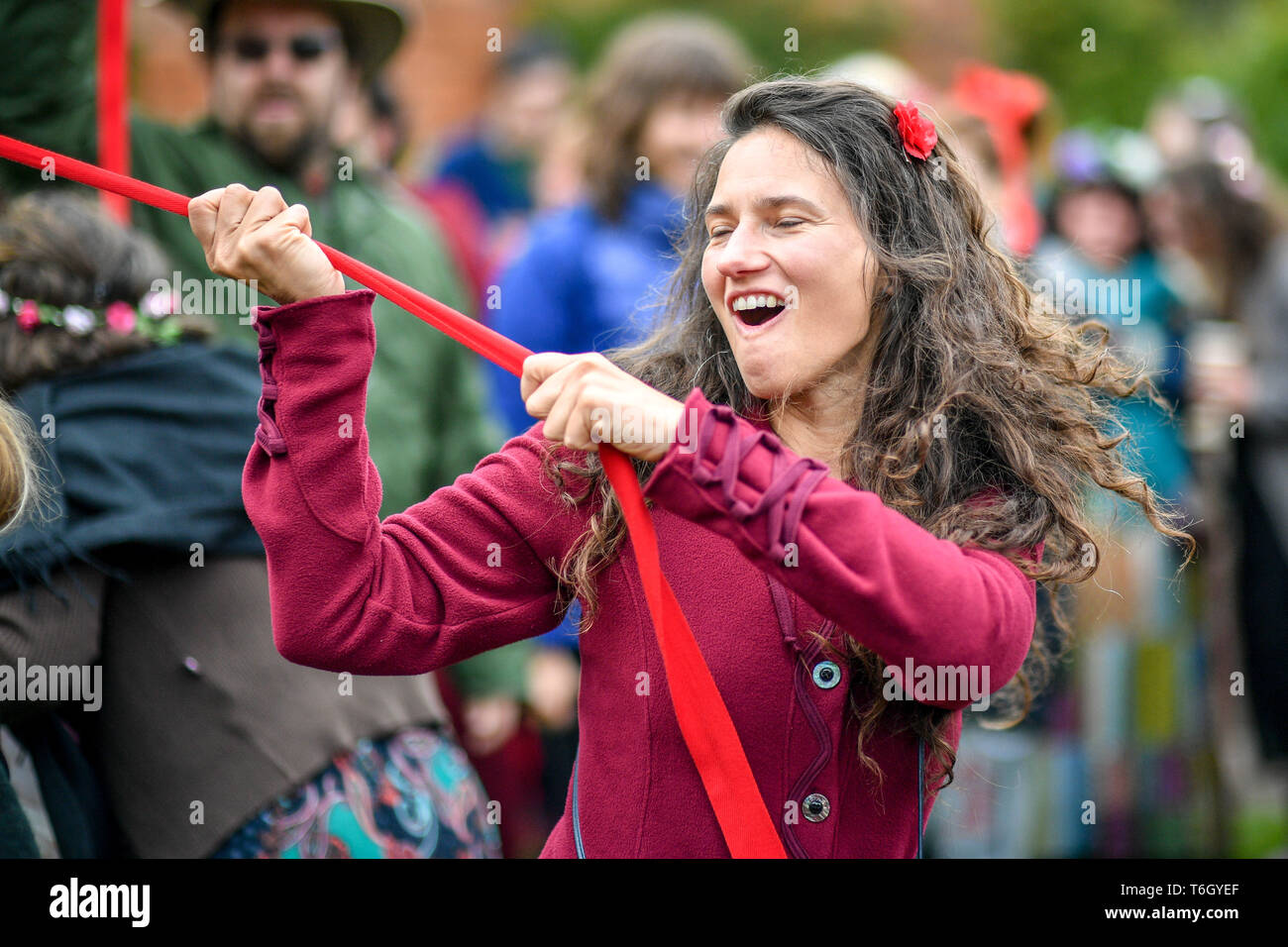 Eine Frau Schlepper auf ihrem Band als Menschen Tanz um den Maibaum während der beltane Feiern an Glastonbury Kelch, wo Menschen zusammenkommen, eine moderne Interpretation des alten Keltischen heidnische Fruchtbarkeit Ritus der Feder zu beobachten. Stockfoto