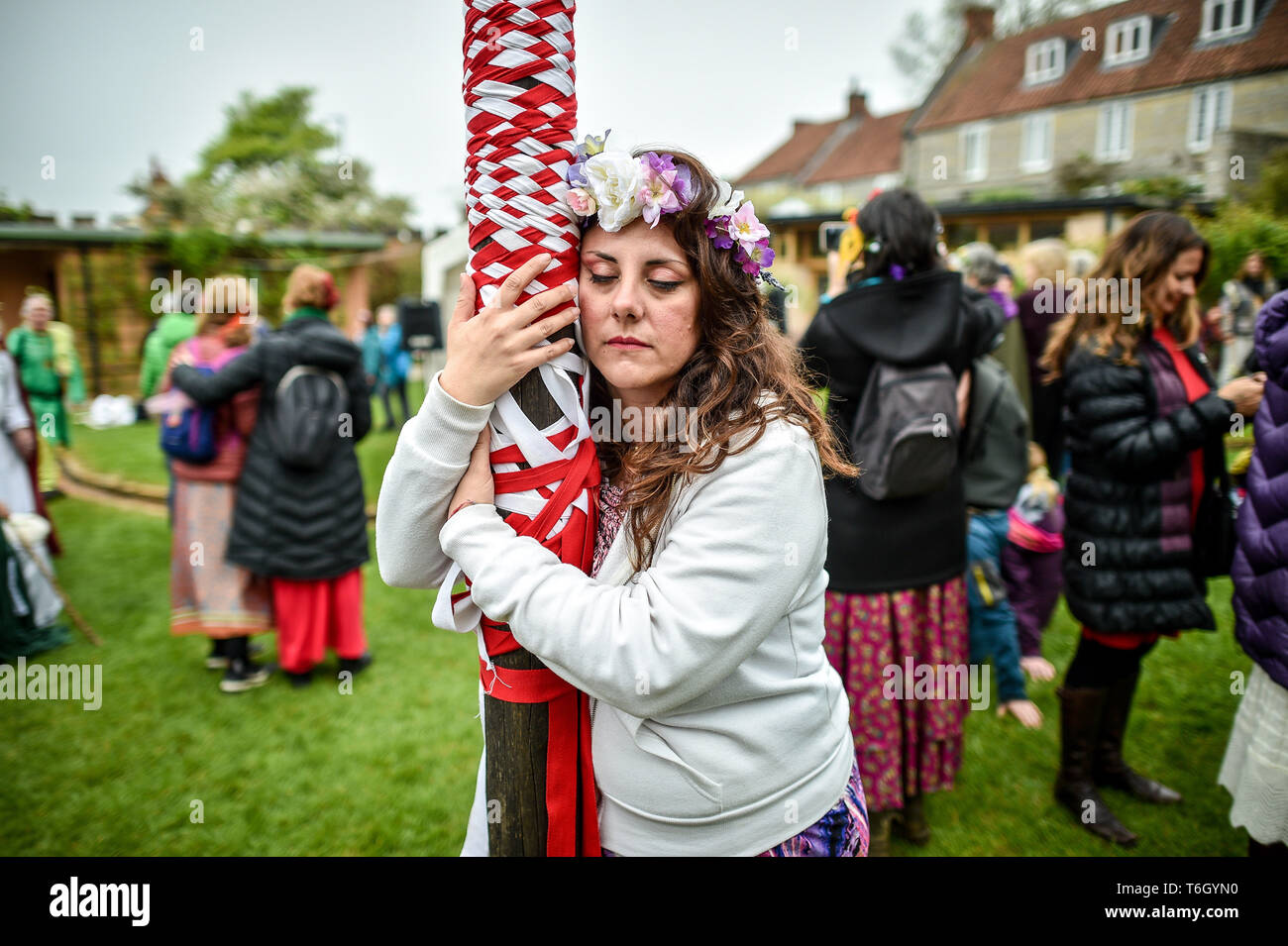 Eine Frau schweigend umarmt den Maibaum während der beltane Feiern an Glastonbury Kelch, wo Menschen zusammenkommen, eine moderne Interpretation des alten Keltischen heidnische Fruchtbarkeit Ritus der Feder zu beobachten. Stockfoto
