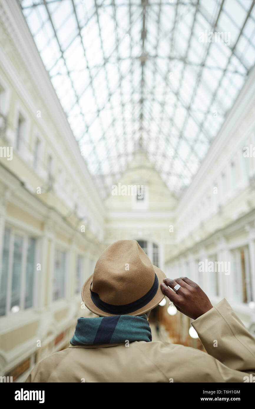 Rückansicht Portrait von trendigen afrikanischen Mann mit Hut stehend in der architektonischen Gebäude mit Glasdach, kopieren Raum Stockfoto