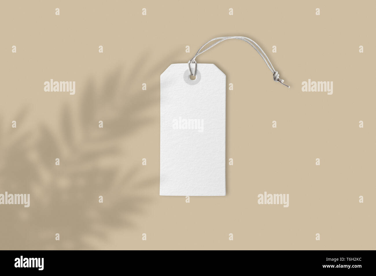 Leere weiße Preis label Tag auf braunem Hintergrund mit kreativen Blume Schatten, Frontansicht mockup mit Kopie Platz, close-up real Bild Stockfoto