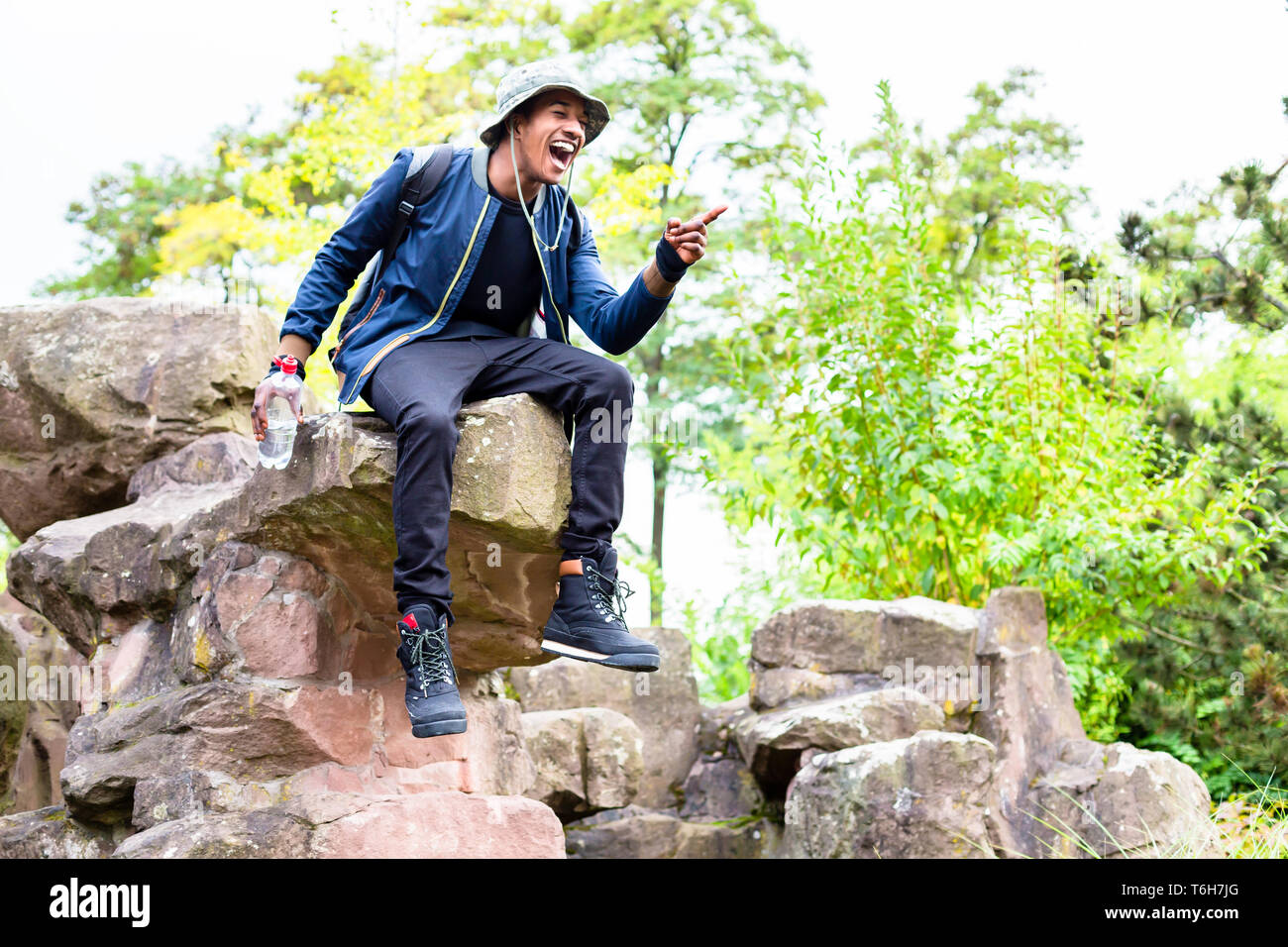 Junge Junge sitzt auf Felsen Zeigefinger lachen Stockfoto