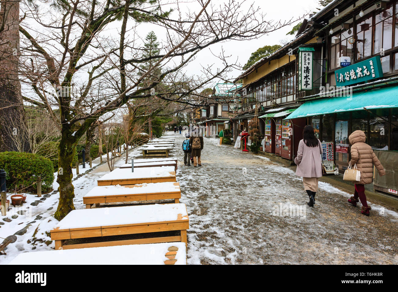 Blick auf Gehweg durch Kenrokuen Gärten, bei der die Zeile der Souvenirläden und Restaurants auf der einen Seite und leeren Schnee Tabellen auf der anderen. Kanazawa, Japa Stockfoto