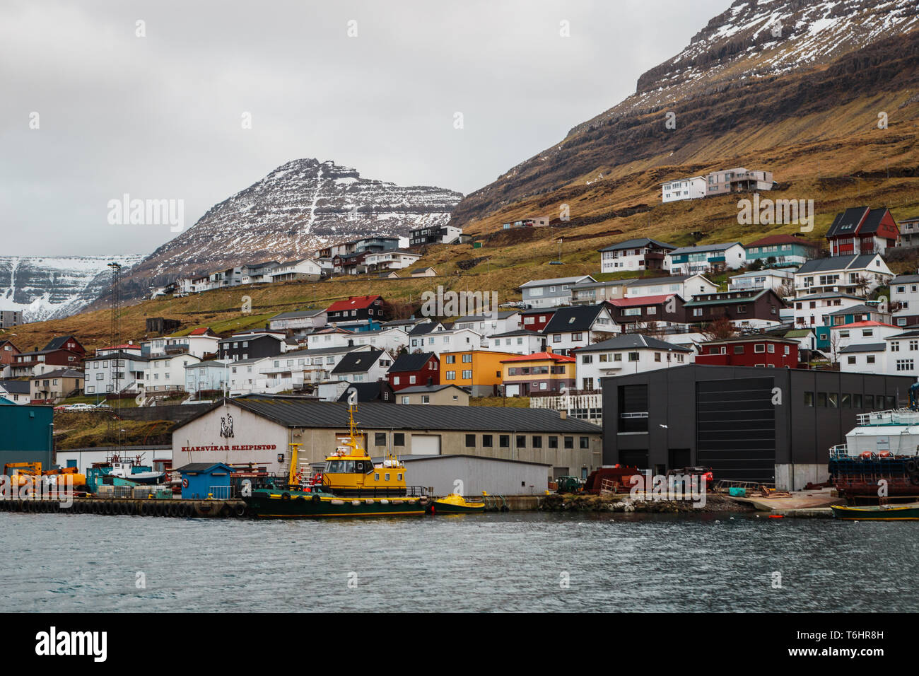 Malerischen bunten Häuser in der kleinen Stadt Klaksvík vor schneebedeckten Bergen wie von einer Fähre zur Insel Kalsoy gesehen (Färöer Inseln) Stockfoto