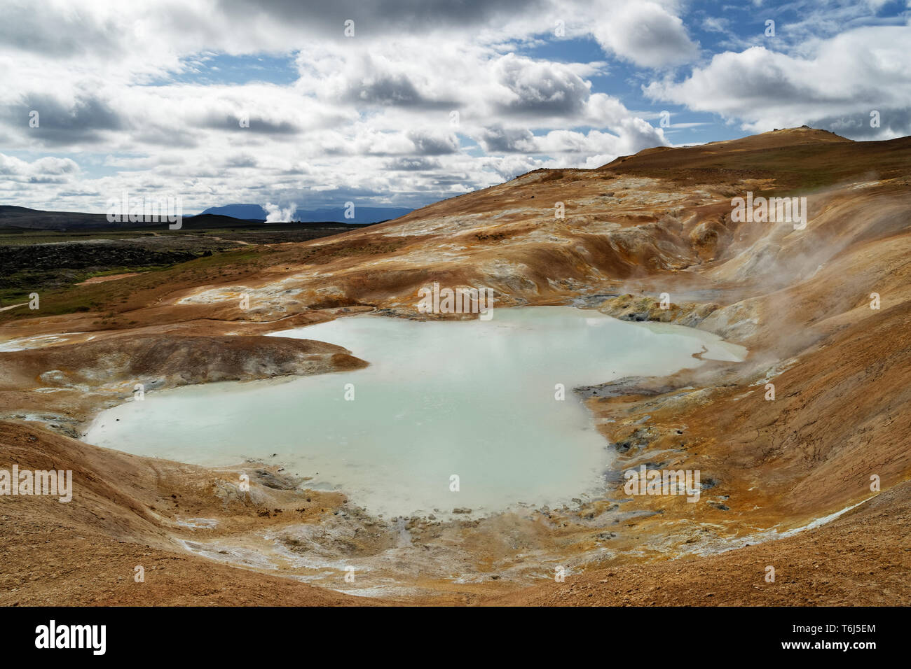 Große vulkanische Landschaft mit Ocker, rote und gelbe Farbtöne im Vordergrund, ein Teich mit Thermalwasser im Vordergrund und Schwefel Quellen gefüllt, Risi Stockfoto