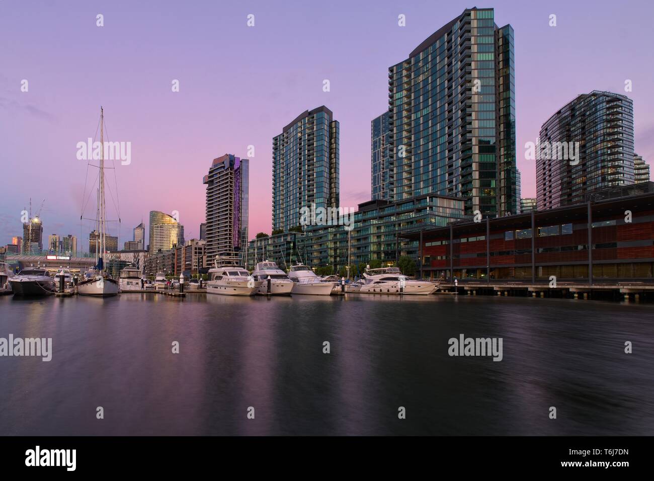 Victoria Harbour Promenade Melbourne Docklands Marina und hohen Apartment Gebäude in rosa und lila Farbtönen von Sunset Stockfoto