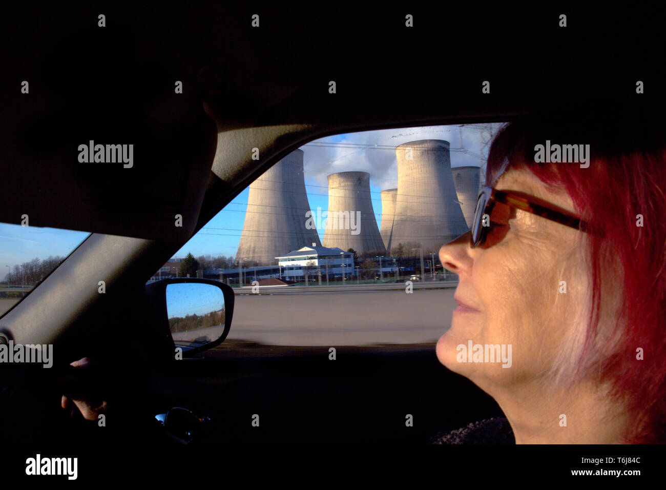 Frau, die ein Auto mit einem Kraftwerk in Aussicht. Stockfoto