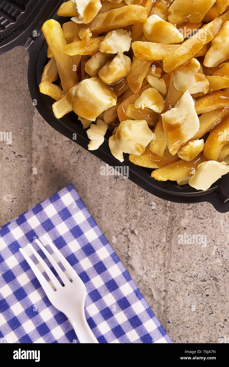 Poutine in einem takeout Container. Mit Pommes frites, Rindfleisch, Soße und Quark Käse gekocht. Kanadische Küche. Stockfoto