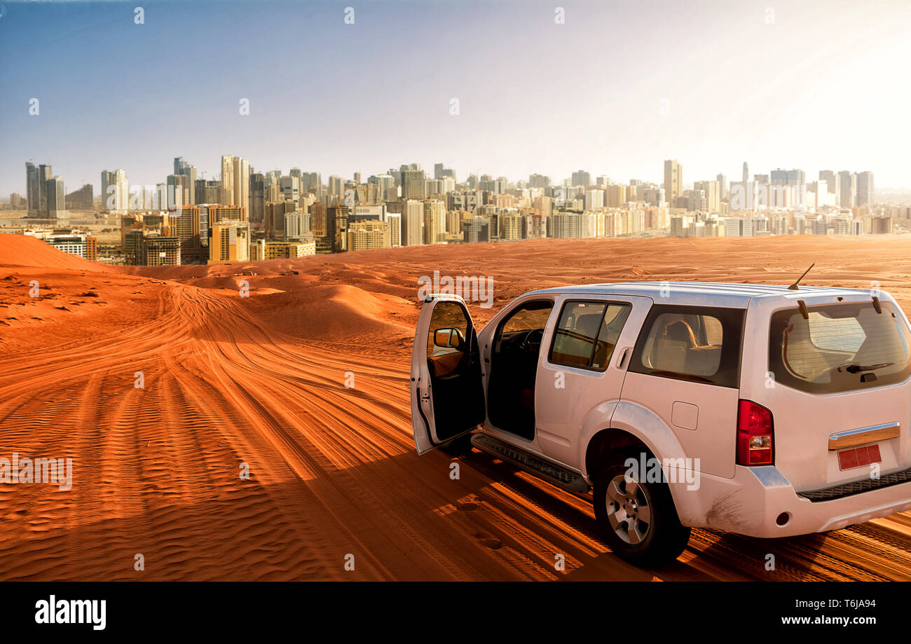 Off-road-Fahrzeug auf eine Wüste Sand Track und der Stadt im Hintergrund Stockfoto