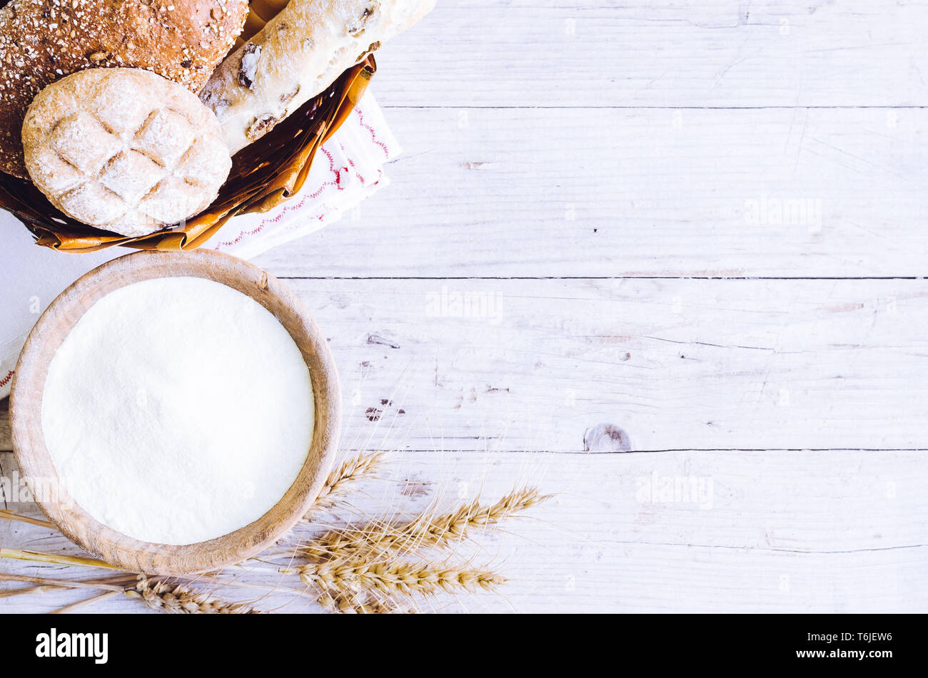 Verschiedene Arten von traditionellen Italienischen frisch gebackenes Brot und Brötchen mit Schüssel Mehl auf hölzernen Tisch Hintergrund. Rustikale Vintage Style. Ansicht von oben. Co Stockfoto