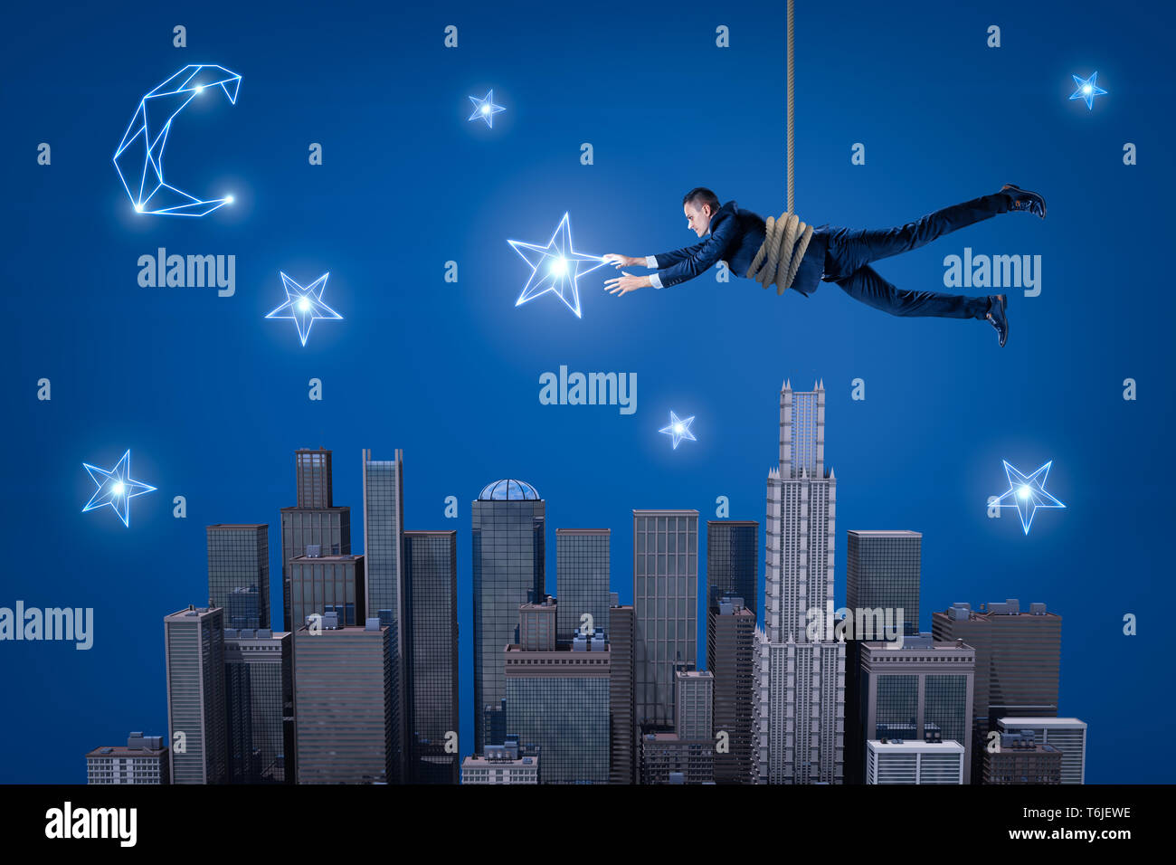 Ein Geschäftsmann hängend an einem Seil über eine Nacht Stadt und versuchen, einen Stern am Himmel zu fangen. Stockfoto