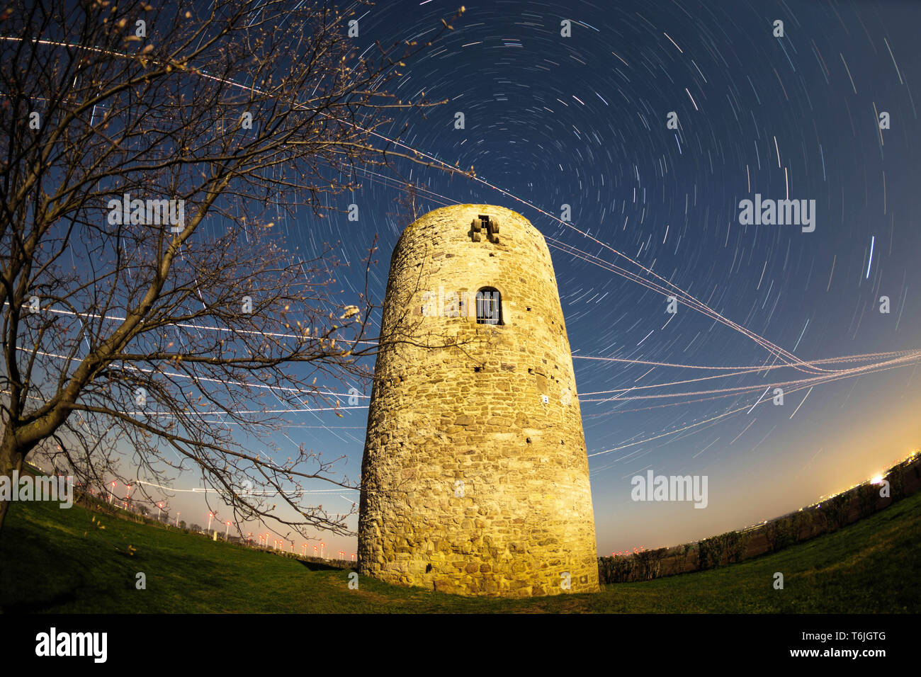 Alten Wachturm in der Nacht vom Vollmond beleuchtet, mit rotierenden Sky (Star Wanderwege) und ebene Wanderwege (Foto mit Fish Eye Objektiv aufgenommen) Stockfoto