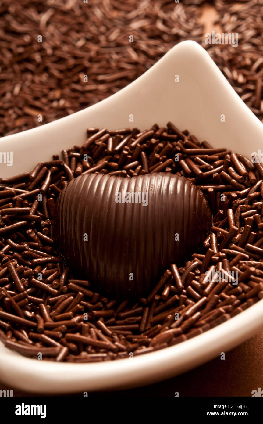 Schokolade in Herzform Bonbon auf einem Bett von Schokolade besprüht Stockfoto