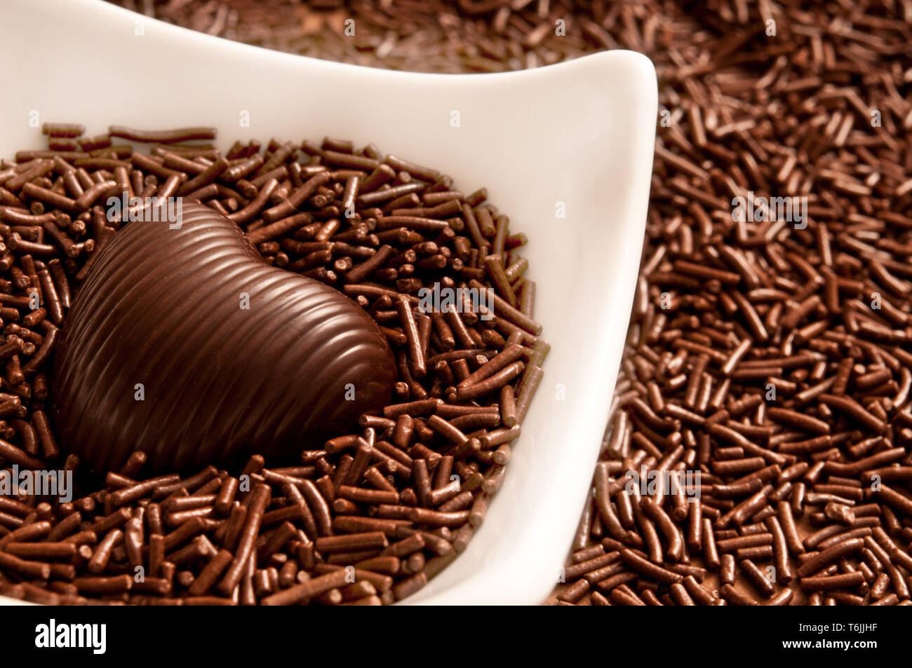 Schokolade in Herzform Bonbon auf einem Bett von Schokolade besprüht Stockfoto