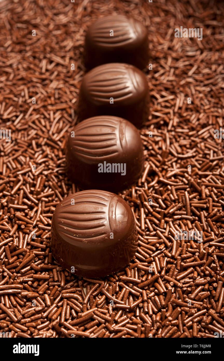 Reihe von Pralinen oder Bonbons auf Schokolade besprüht Stockfoto