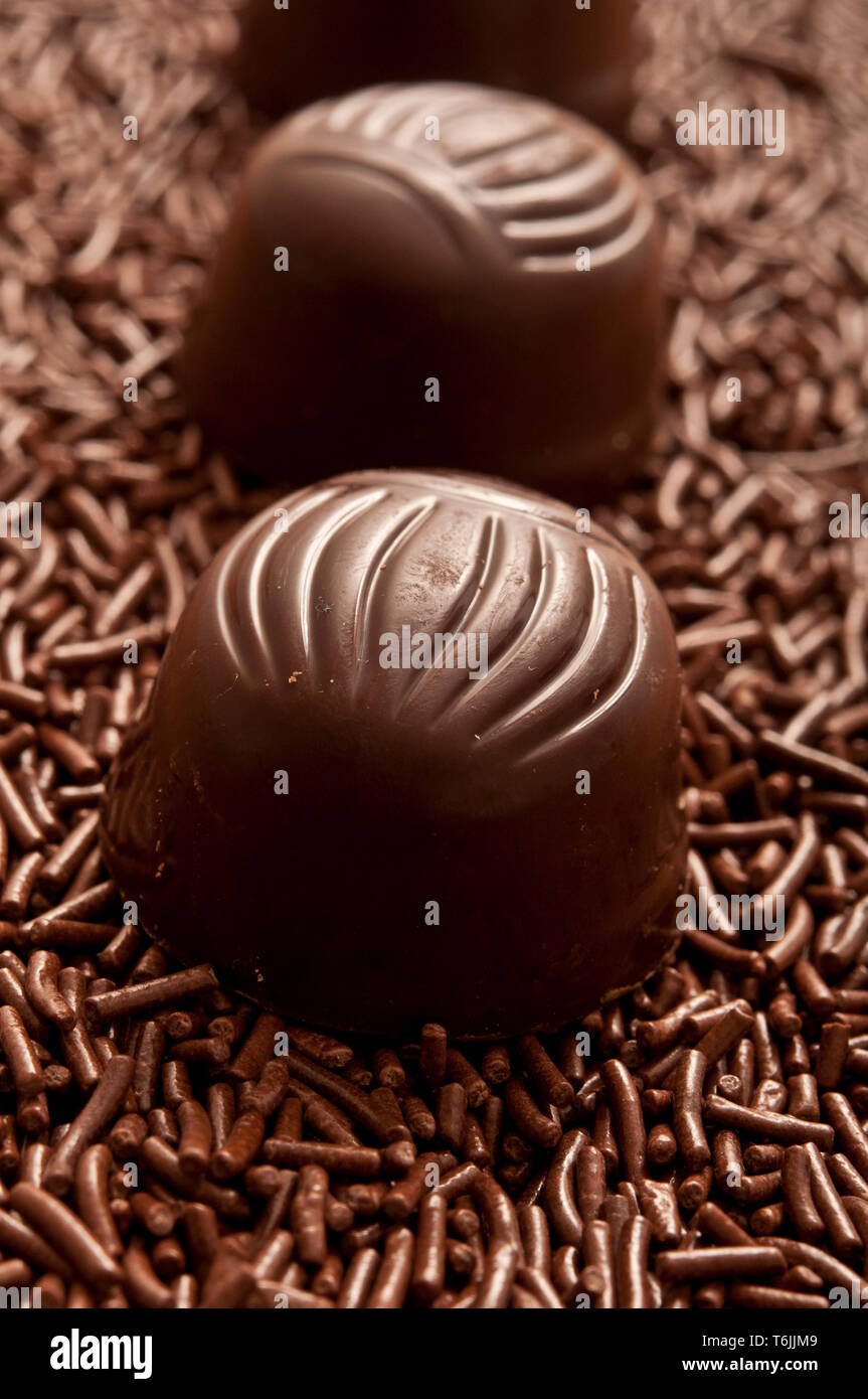 Reihe von Pralinen oder Bonbons auf Schokolade besprüht Stockfoto