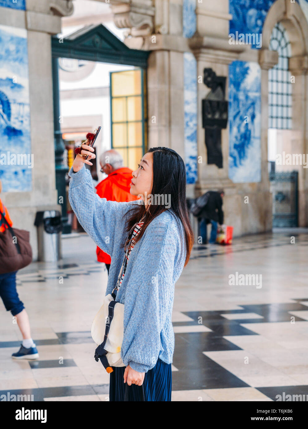Porto, Portugal - April 29, 2019: Asiatische touristische Bilder im historischen Bahnhof Sao Bento in Porto, Portugal. Wand ist in b Stockfoto
