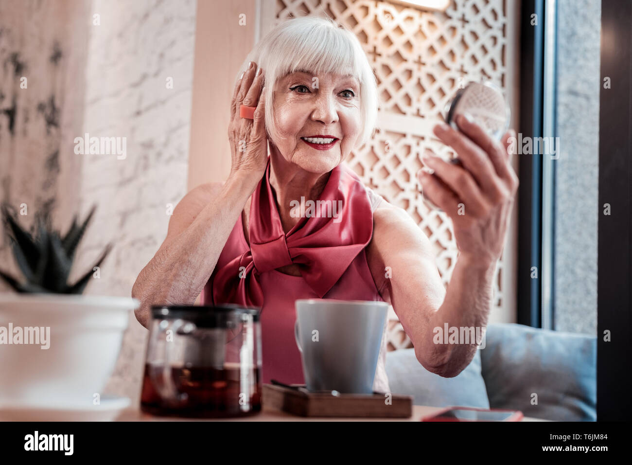 Kurzhaarige gepflegt alte Frau wartet auf Ihr Datum in einem Cafe Stockfoto