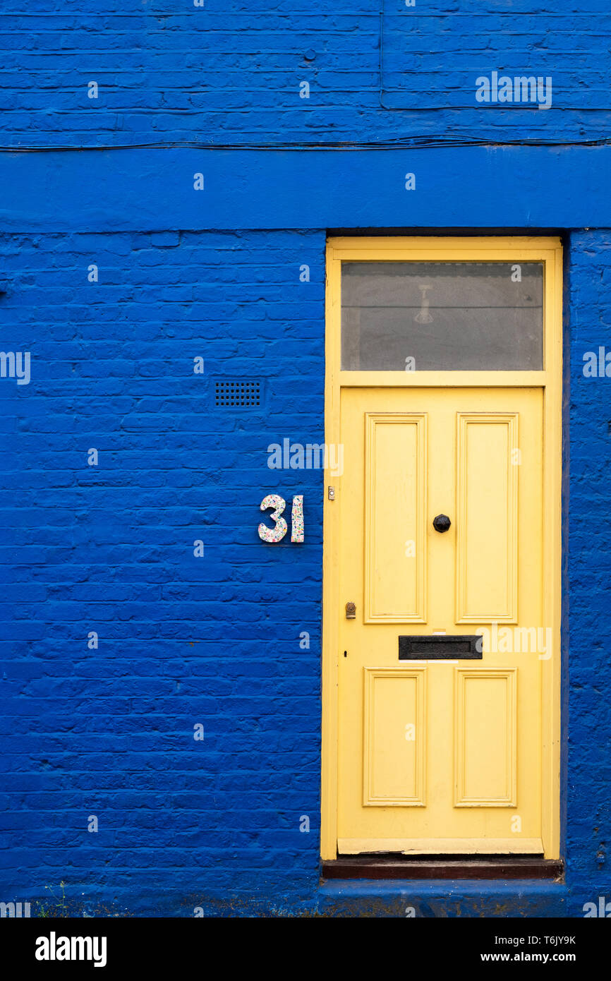 Gelbe Tür in einem dunklen Blau lackiert. St Lukes Mews, Notting Hill, London, England Stockfoto