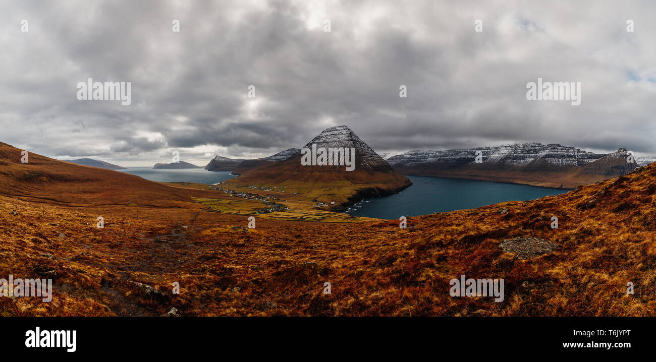 Panoramablick vom Kap Enniberg in das kleine Dorf Viðareiði, seine Fjorde, Kunoy Insel und schneebedeckte Berge (Färöer, Dänemark, Europa) Stockfoto