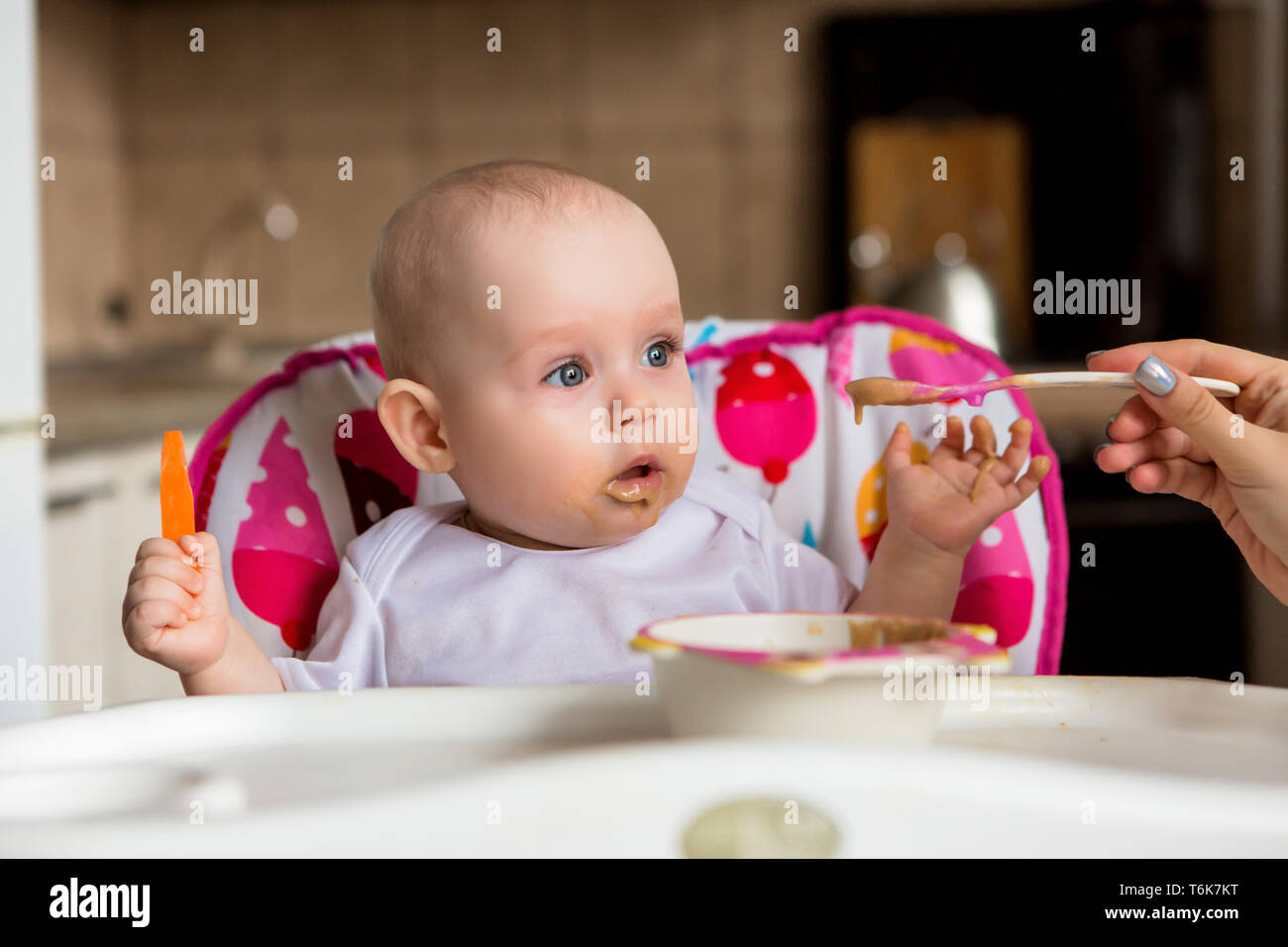 Baby ist 8 Monate und isst unabhängig. Der erste lure Baby. Das Baby mit blauen Augen nicht Gemüsebrei zu essen. mom Feeds von einem kleinen Kind' Stockfoto
