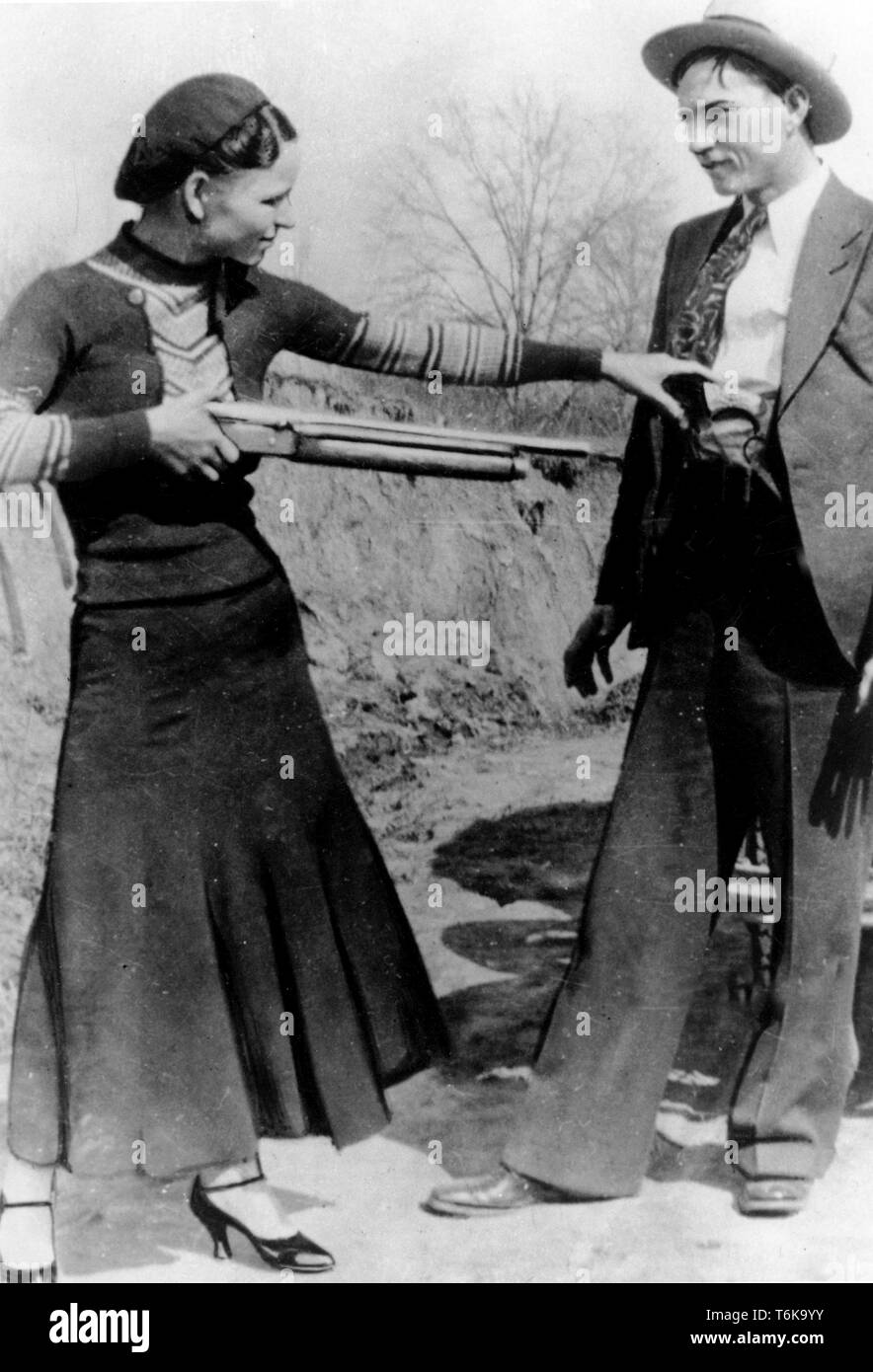 Bonnie und Clyde und Bonnie Parker soll spielerisch eine Pistole an Clyde Barrow. Bonnie Elizabeth Parker (1910-1934) und Clyde Chestnut Barrow (1909 - 1934) amerikanischer Verbrecher, die die mittleren Staaten der USA mit ihrer Bande während der Großen Depression reiste, raubt Banken und Geschäfte, und tötete mehrere Menschen Stockfoto