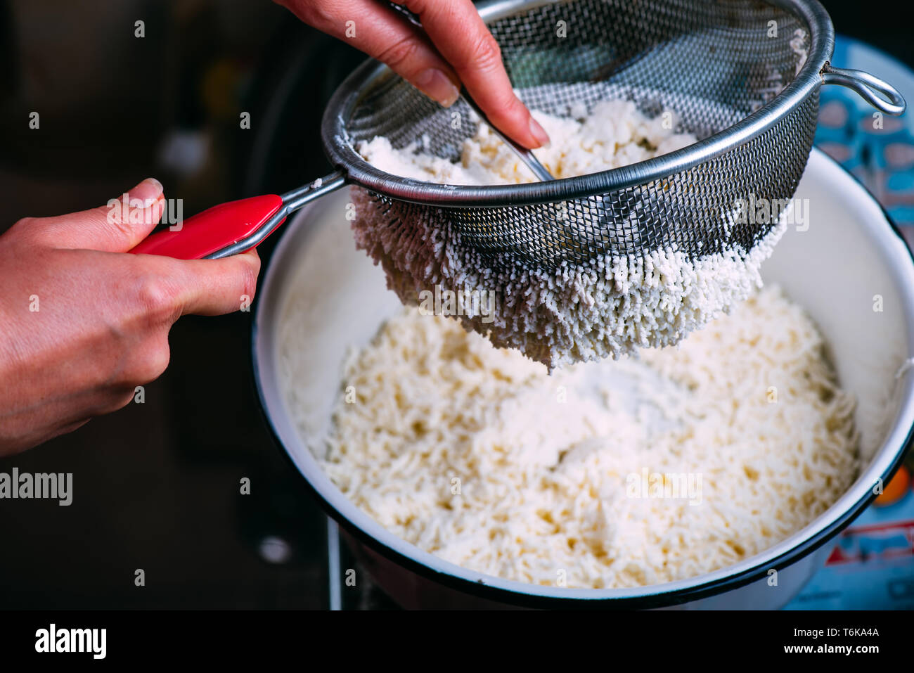 Der Prozess des Kochens hausgemachte Hüttenkäse. Hüttenkäse ist durch ein Sieb aus Molke gefiltert. Stockfoto