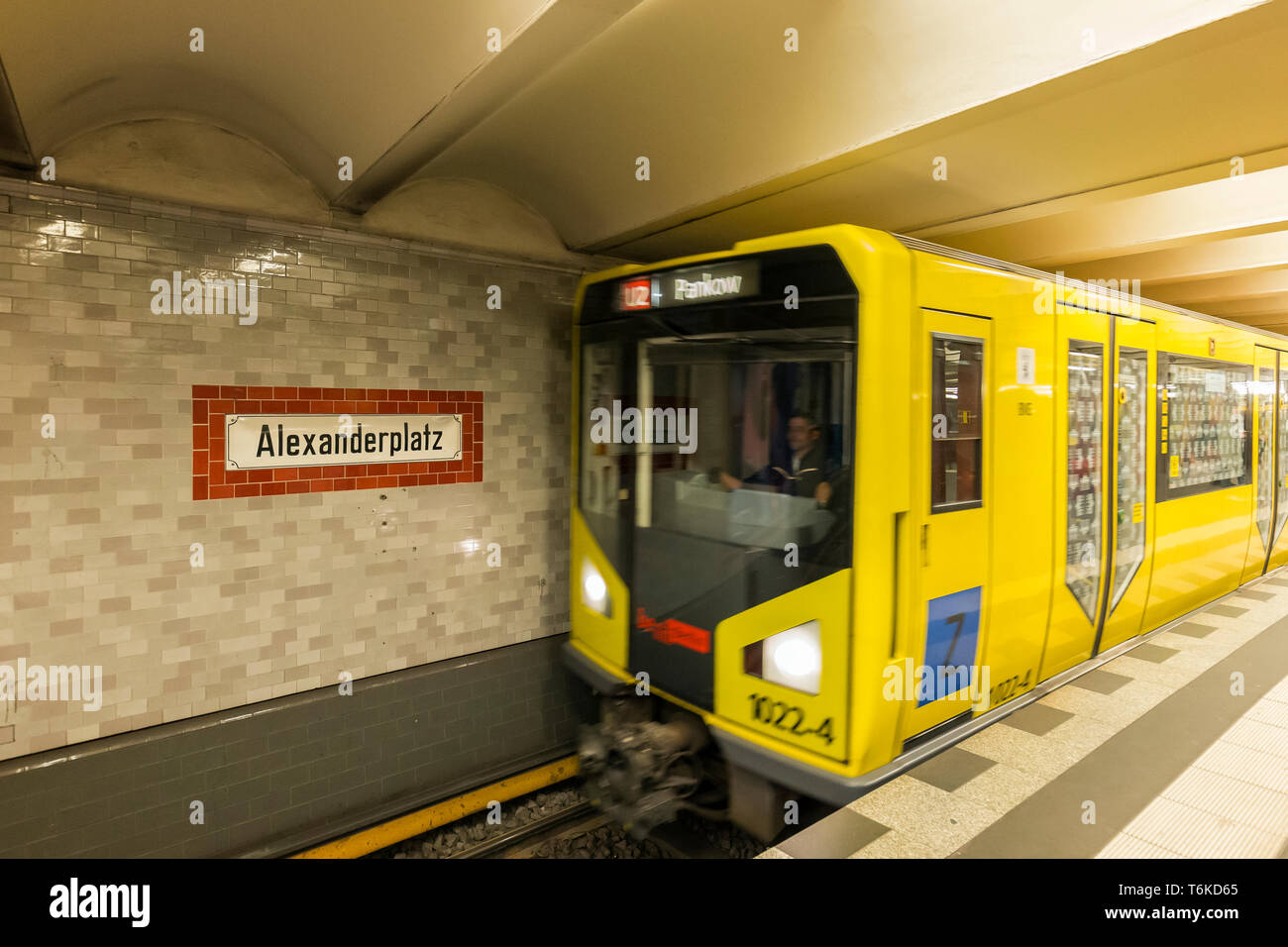 Alte Zeichen der Alexanderplatz U-Bahn U-Bahn / U-Bahn Station auf eine Kachel Wand und gelbe U-Bahn Zug nähert sich in Berlin. Stockfoto
