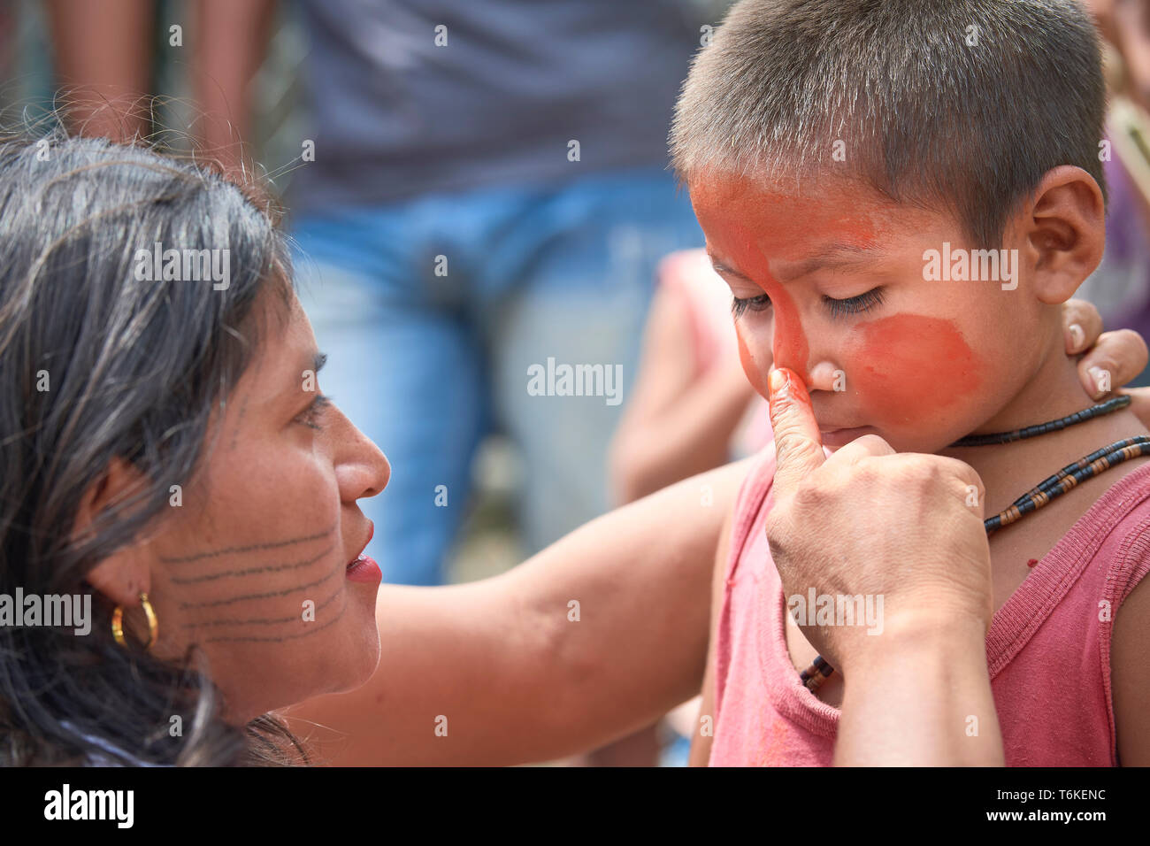 Eine Frau, die Farben eines Kindes Gesicht mit urucum, bevor ein Marsch der indigenen Bevölkerung durch die Straßen von Atalaia Norte im brasilianischen Amazonasgebiet. Stockfoto