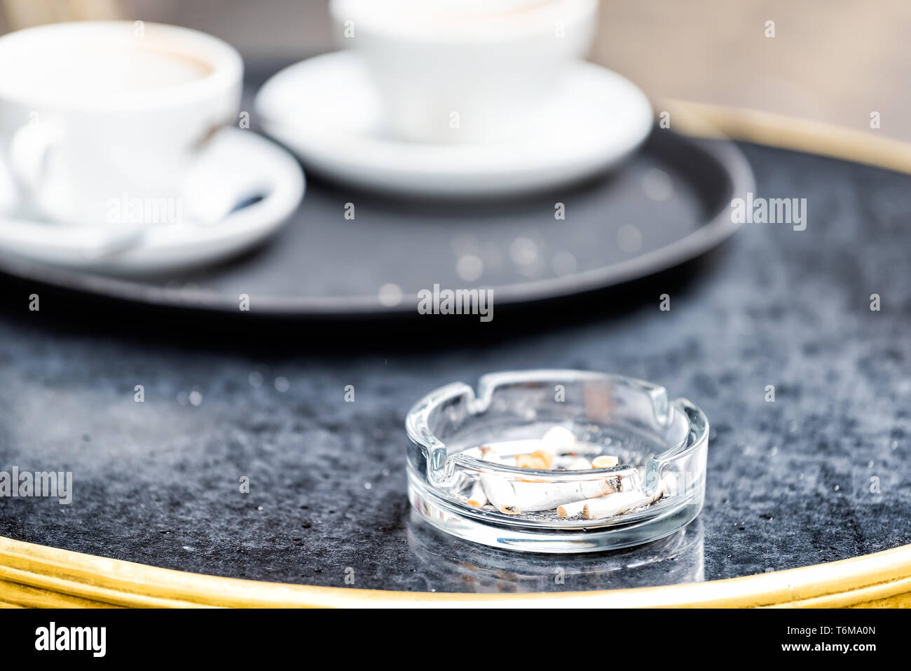 Nahaufnahme der Tisch mit Kaffee oder Tee am Nachmittag im Café im Freien mit niemand in London, UK und Aschenbecher mit Zigaretten Stockfoto