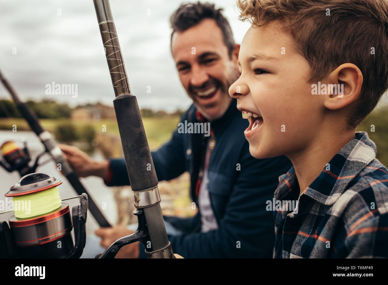 Nahaufnahme von einem lächelnden Mann angeln zusammen mit seinem Sohn in einem See. Lächelnd mann an seinen Sohn genießen, Angeln auf einen angenehmen Tag. Stockfoto