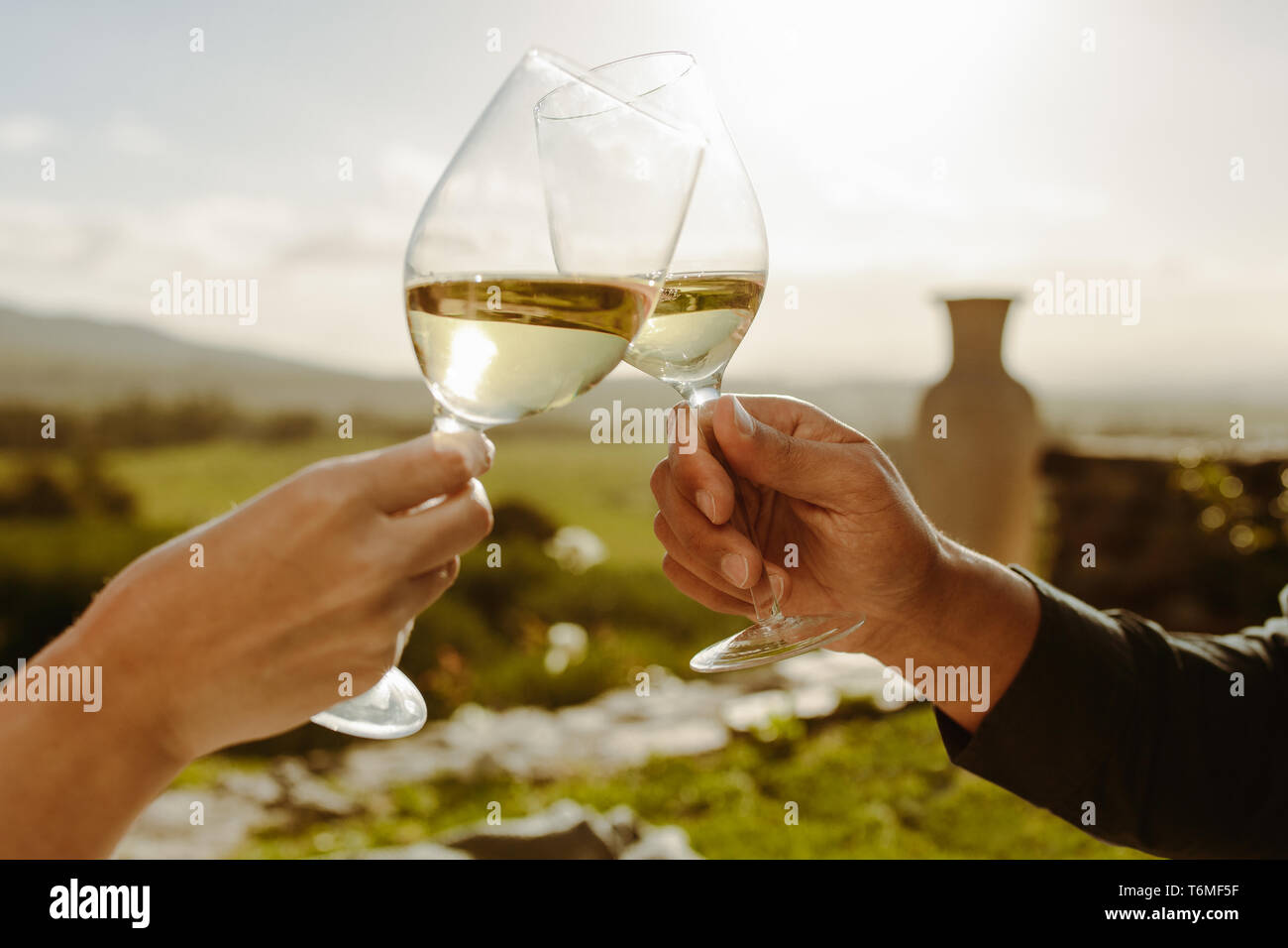 In der Nähe der Hände von ein paar toasten Gläser Weisswein. 7/8 Schuß von ein paar toasten Wein sitzen in einem Weingut. Stockfoto