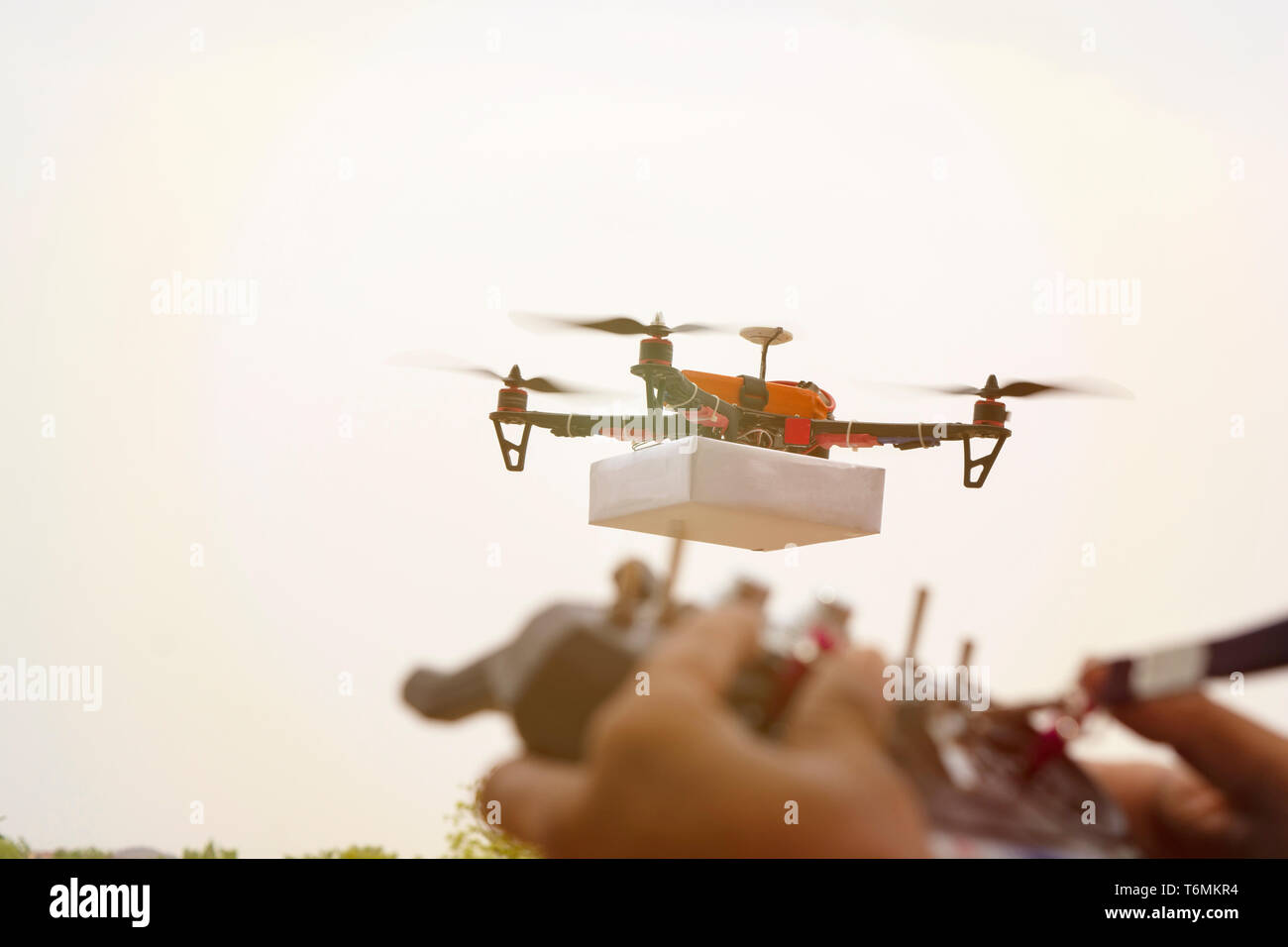 Nahaufnahme des unscharfen Hände opertaing Drone sender, empfänger Controller, Controller in der konzentrieren, während Drohne im Fokus der Hintergrund ist. Stockfoto