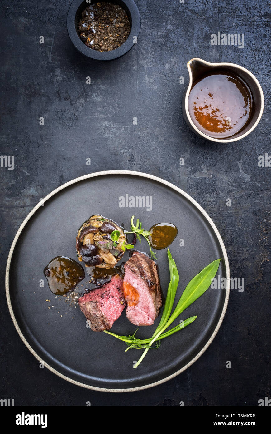 Traditionelle italienische Grill alter geschnittenes Rinderfilet mit Bärlauch und pioppinos als Draufsicht auf einer Platte Stockfoto