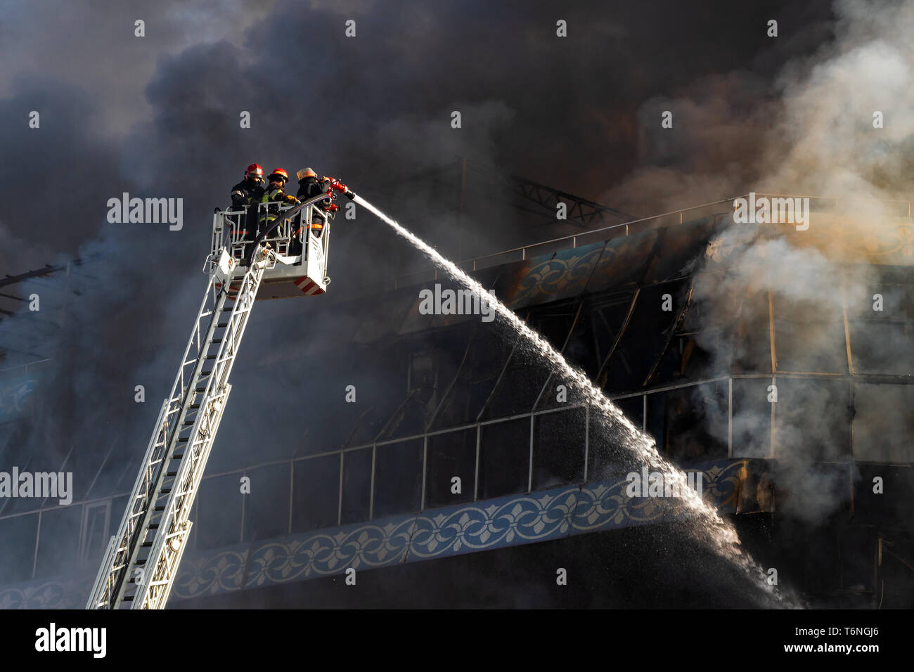 Feuerwehrmänner auf der Treppe ein großes Feuer löschen Stockfoto