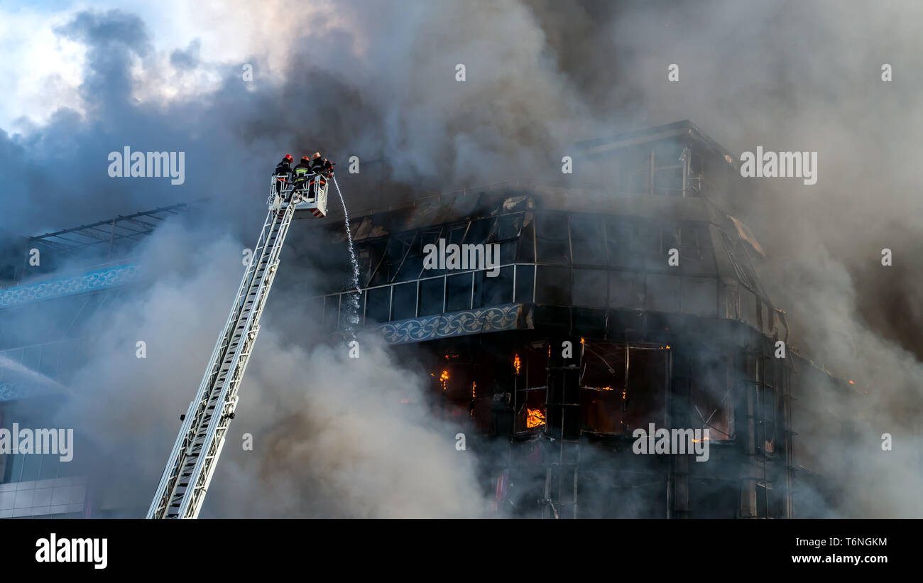 Feuerwehrmänner auf der Treppe ein großes Feuer löschen Stockfoto
